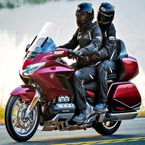 Deux personnes casquées sur une moto de tourisme rouge.